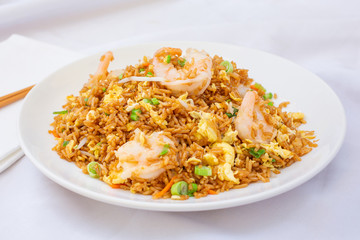 A view of a plate of Chinese shrimp fried rice, in a restaurant or kitchen setting.