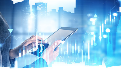 Woman trader using tablet in office, graph