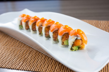 A view of an orange dragon roll sushi plate in a restaurant or kitchen setting.