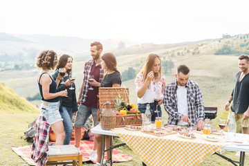 Happy friends eating at picnic lunch in italian vineyard outdoor - Young people having fun on gastronomic weekend tuscany tour - Friendship, summer and food concept - Main focus on center man face
