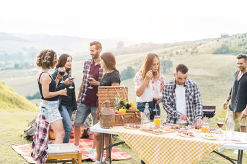Happy friends eating at picnic lunch in italian vineyard outdoor - Young people having fun on...