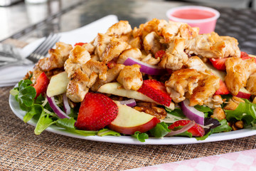 A closeup view of a chicken fruit salad, in a restaurant or kitchen setting.