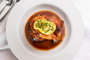 A top down view of a plate of lemon chicken in a restaurant or kitchen setting.