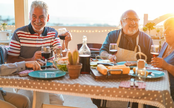 Group Of Happy Senior Friends At Barbecue Meal In Terrace Outdoor - Mature Old People Drinking Wine At Patio Bbq Dinner - Main Focus Right Man Face - Joyful Elderly Lifestyle Concept