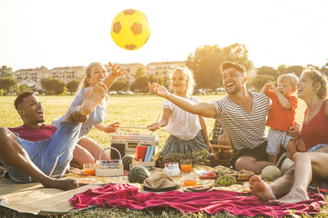 Happy families doing picnic in city park - Young parents having fun with their children in summer time eating, drinking and laughing together - Love and chlidood concept - Main focus on faces