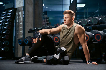Bodybuilder posing on floor in gym.