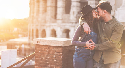 Young couple having tender moments in Rome with Colosseum as background - Lovers having fun during europe vacation tour - Travel, love and romance concept - Focus on faces