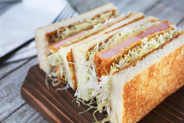 A closeup view of a Japanese Katsu Ham Sando in a restaurant or kitchen setting.