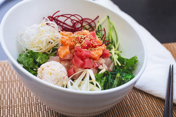 A view of a bowl of sashimi salad, in a restaurant or kitchen setting.