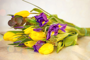 Beautiful bouquet of yellow tulips and blue irises on a light background. Floral background, spring card with yellow and blue flowers, copy space,