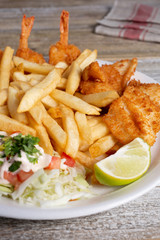 A view of a plate of deep fried shrimp and french fries, in a restaurant or kitchen setting.