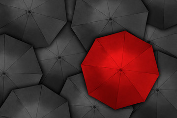 Red umbrella over many dark ones