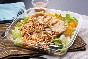 A view of a container of Asian Chicken Salad, in a restaurant or kitchen setting.