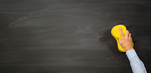 Hand with sponge erases the chalkboard