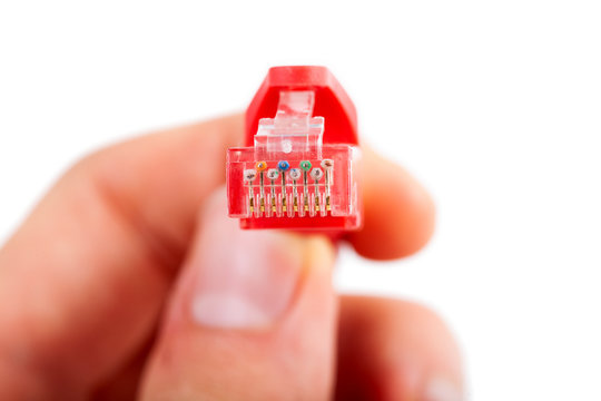 Man holding an 8P8C RJ-45 crimped red ethernet connector, unshielded twisted pair UTP straight through cable end, macro, detail, closeup. Internet cable simple connection concept, isolated on white