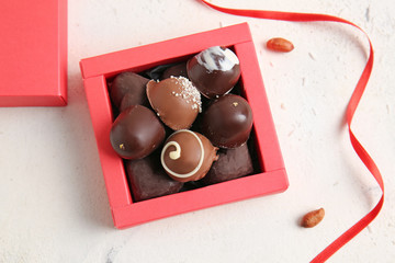 Box with delicious chocolate candies on light background