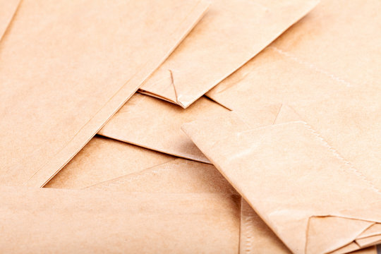 A pile of many small brown eco new paper recyclable food bags detail abstract background texture pattern macro, closeup. Lots of simple light food packaging stacked abstract backdrop