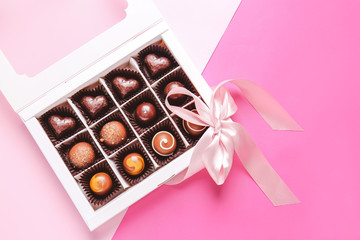 Box with delicious chocolate candies on color background