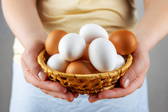 Female hands hold a basket of fresh chicken eggs, close-up, selective focus, shallow depth of field. The concept of healthy food, spring religious holidays.