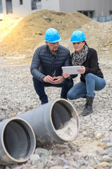 Construction manager and architect read their notes on a tablet  on a buildding site