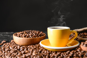 Cup of hot coffee and beans on table