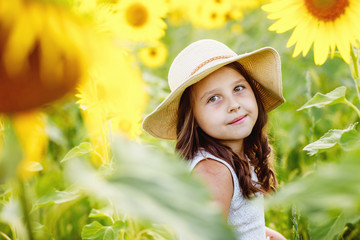 Cute girl(child) playing in the sunflowers field with sunflowers.