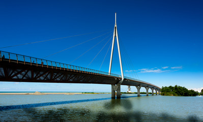 A modern bridge connecting two islands with pastel blue skies