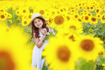 Cute girl(child) playing in the sunflowers field with sunflowers.