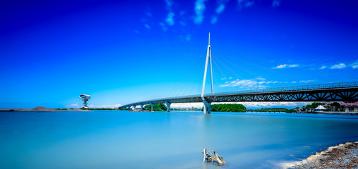 A modern bridge connecting two islands with pastel blue skies