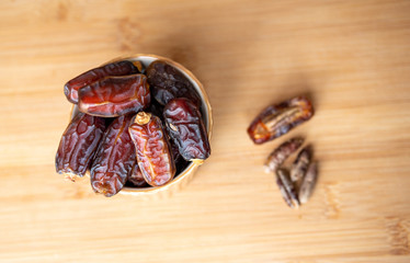 dates in a bowl on a wooden table . Top view.