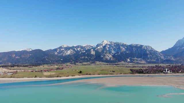 Luftaufnahme des noch nicht vollst&auml;ndig gef&uuml;llten Forggensee mit dem Lech und den Ammergauer Bergen im R&uuml;ckw&auml;rtsflug