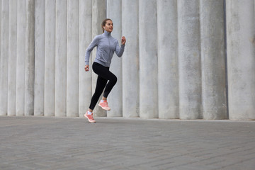 Full length of young sporty woman jogging while exercising outdoor