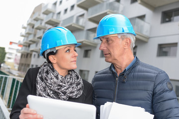 Construction manager and architect are reading their notes on a site