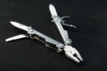 Multitool is a multi-functional tool on a black background. The concept of an expanded multi-tool with free space.