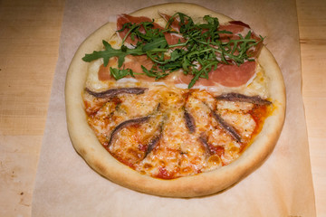 Pizza artigianale fatta in casa al forno con rucola acciughe salsiccia mozzarella pomodoro