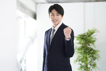 カメラ目線でガッツポーズをする日本人男性ビジネスマン
