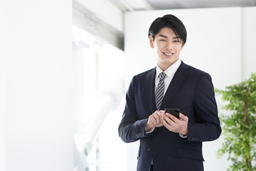 笑顔でスマホを操作する日本人男性ビジネスマン
