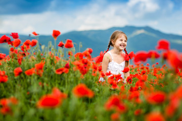 Fototapeta na wymiar Cute child girl in poppy field