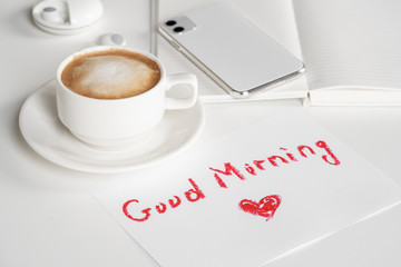 Cappuccino cup and good morning wish written by lipstick on white background. Romance and love concept
