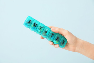 Obraz premium Female hand holding box with pills on color background