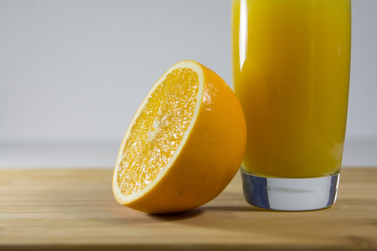 Cut Juicy Orange And A Glass Of Bright Fresh Orange Juice Stand On The Kitchen Table