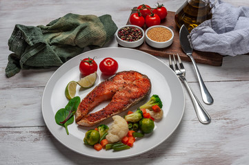 Fried salmon fishes and boiled vegetables on plate