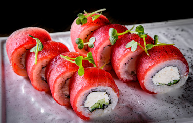 sushi roll with tuna, cream cheese, cucumber, rice in plate on black wooden table background