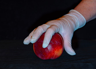 A woman's hand in a rubber glove and a red Apple .