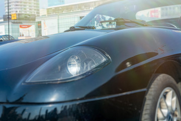 Obraz na płótnie Canvas car under the sun on the street. car front, headlight, wheel. closeup