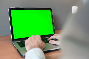 Young boy studying at home on a computer with mock-up green screen at his room. Quarantine and covid19 concept