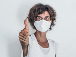 woman social distancing from corona virus covid-19 wearing a protective face mask having her thumb...
