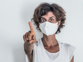 woman protecting from corona virus covid-19 wearing a protective face mask pointing with finger