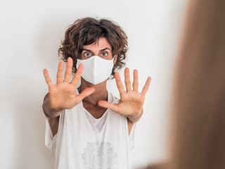 woman social distancing from corona virus covid-19 wearing a protective face mask holding up hands saying stop to another person