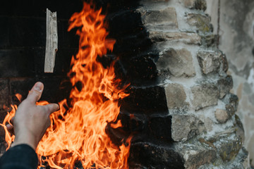 Obraz premium hand throwing a piece of firewood on fire flames
